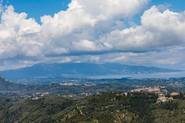 Yunanistan 'daki İyon Denizi' ndeki Korfu adasının güzel bir manzarası. Bir sürü yeşil bitkisi olan dağlar. Adanın üzerinde kalın bulutlar.