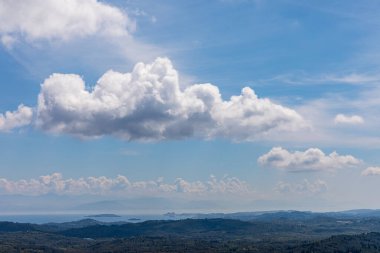 Yunanistan 'daki İyon Denizi' ndeki Korfu adasının güzel bir manzarası. Bir sürü yeşil bitkisi olan dağlar. Adanın üzerinde kalın bulutlar.