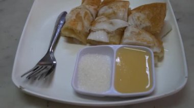 Genç hindistan cevizi roti, paslanmaz çelik çatal bıçak, şeker ve konsantre süt içeren plastik bir tabağa konur.
