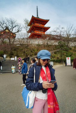 Kızıl Japon tapınağının önünde cep telefonu çalan Asyalı kadınlar.