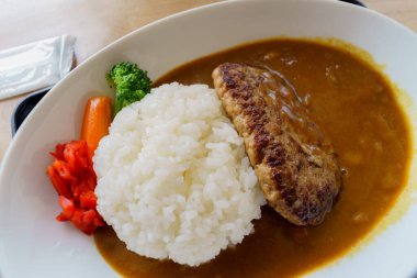 Beyaz tabakta körili ve pirinçli Hamberg.