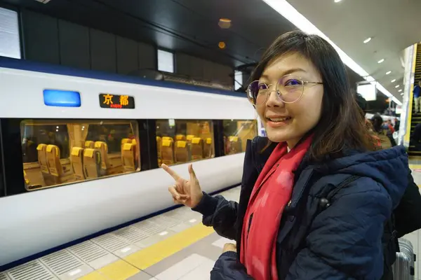 Asyalı kadınlar metro istasyonundaki Japon trenini işaret ediyorlar.