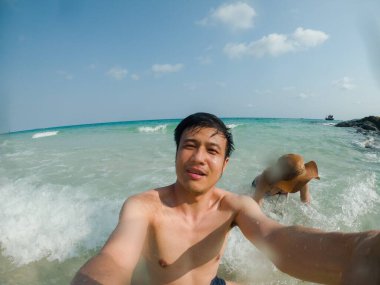 Asyalı çift denizde selfie çekiyor.