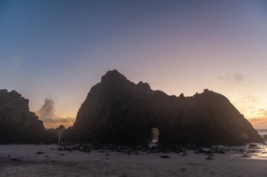 Gün batımında Pfeiffer Sahili 'ndeki anahtar deliği kemeri kayasının etkisi.