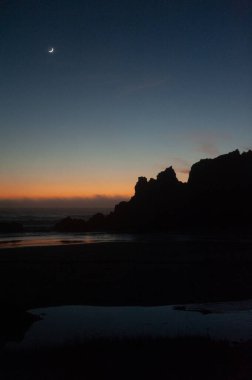 Güneş battıktan sonraki altın saat boyunca kremalı ay sahili vurguluyor..