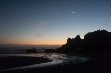 Güneş battıktan sonraki altın saat boyunca kremalı ay sahili vurguluyor..