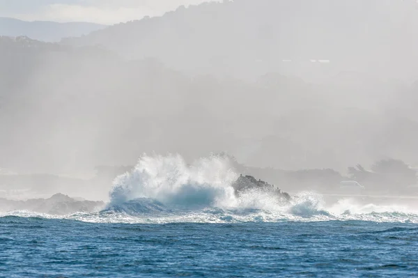 A giant wave is breaking at a cliff in Monterey Bay.