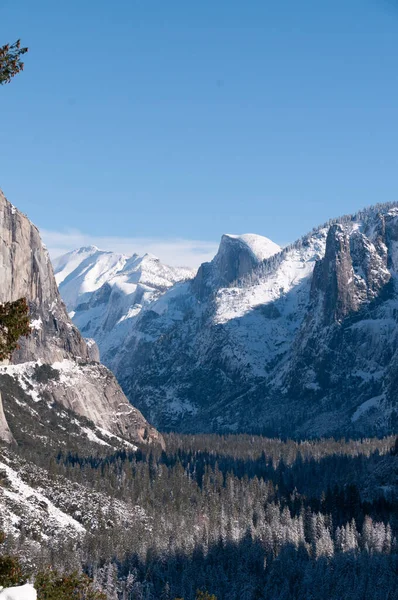 Landscape shot of Yosemite Valley, from the tunnel view lookout, showing El Capitan and Half-dome in the distance.