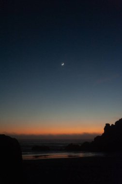 Güneş battıktan sonraki altın saat boyunca kremalı ay sahili vurguluyor..