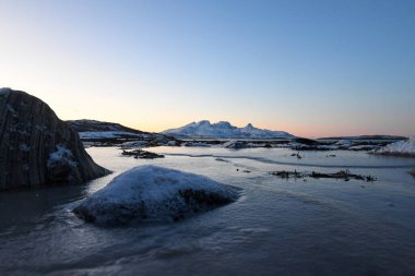 Wide angle landscape shot of the snow covered mountains and beach near Mjelle, part of the Bodo community in Arctic Norway, during the brief period of daylight in the arctic winter.