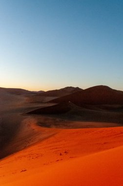 Namibya Sossusvlei kumullarının dış görüntüsü ünlü kum tepeciklerinin yakınında, güneş doğarken.