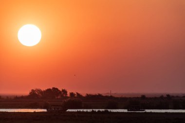 Telephoto shot of the setting sun over the chobe river on a bright winter afternoon in Botswana.