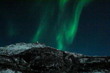 Kuzey Işığının Parlak Yeşil Renkleri, Aurora Borealis Arktik Norveç 'teki Mjelle plajının üzerindeki Gece Gökyüzünü aydınlatıyor..