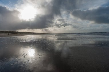 Hollanda, Kuzey Hollanda 'da Egmond aan Zeen yakınlarındaki sahilde bir su kalıntısına yansıyan bulutlar..
