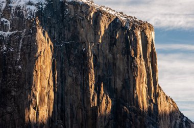 Sabah güneşinin ilk ışıkları Yosemite Ulusal Parkı 'ndaki Sierra dağlarındaki kayalardan yansıyor. Karla kaplı yeni bir gün..