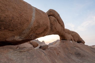 Spitzkoppe yakınlarındaki kaya kemerinin üzerinde gün batımı Namibya 'nın merkezinde ünlü bir granit zirve..