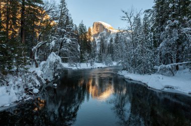 Yarı kubbe, batan güneşle aydınlanırken, Merced nehrine yansıyor. Yosemite Milli Parkı.