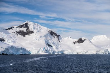 Graham yakınlarındaki sakin bir Antarktika manzarası, Charlotte Körfezi boyunca uzanır, sert yansımaları, engebeli dağları ve etkileyici buzdağlarını vurgular..