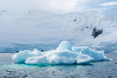 Graham yakınlarındaki sakin bir Antarktika manzarası, Charlotte Körfezi boyunca uzanır, sert yansımaları, engebeli dağları ve etkileyici buzdağlarını vurgular..
