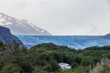 Gri buzulda Refugio Grey 'den Paine Grande' ye yürüyüş yaparken Torres Del Paine Ulusal Parkı, Patagonya, Şili 'deki gri göl boyunca etkileyici bir manzara..