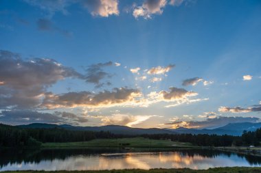 Sunset over a small Lake in the Colorado Rocky Mountains, known as Los Lagos Reservoir Number three. Near Kelly Dahl Campground and the Town of Nederland, CO. clipart