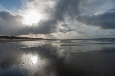 Hollanda, Kuzey Hollanda 'da Egmond aan Zeen yakınlarındaki sahilde bir su kalıntısına yansıyan bulutlar..