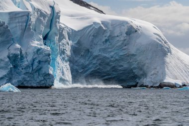 Buz tabakasından buzağı kopan dev bir buz kütlesinin telefonu. Graham Geçidi, Charlotte Körfezi yakınında, Antarktika Yarımadası 'nda.