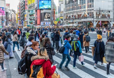 Tokyo, Japonya - 8 Ocak 2020. Birçok insan işlek caddelerde yürüyor ve gün batımında ünlü Shibuya Geçidi 'nden geçiyor. Shibuya Tokyo 'daki en ünlü kavşaklardan biridir..