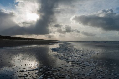 Hollanda, Kuzey Hollanda 'da Egmond aan Zeen yakınlarındaki sahilde bir su kalıntısına yansıyan bulutlar..