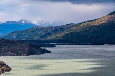 Paine Grande 'den Refugio Grey' e yürüyüş yaparken Torres del Paine Ulusal Parkı 'ndaki gri göl boyunca etkileyici bir dağ manzarası, Patagonya, Şili.