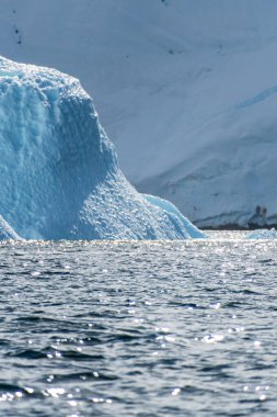 Graham yakınlarındaki sakin bir Antarktika manzarası, Charlotte Körfezi boyunca uzanır, sert yansımaları, engebeli dağları ve etkileyici buzdağlarını vurgular..