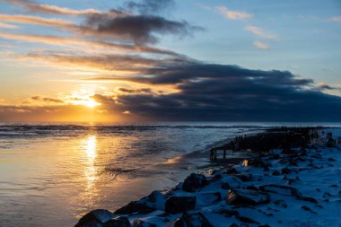 Güney İzlanda 'daki Jokulsarlon buzulu gölünün yakınındaki elmas plajında eriyen buzda, altın saat güneş ışığı kırılıyor..