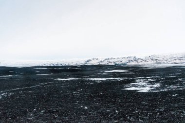 Kışın İzlanda 'nın güney kıyısı boyunca Solheimasandur yakınlarındaki siyah lav plajlarının etkisi