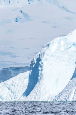 Graham yakınlarındaki sakin bir Antarktika manzarası, Charlotte Körfezi boyunca uzanır, sert yansımaları, engebeli dağları ve etkileyici buzdağlarını vurgular..