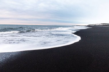 Kışın İzlanda 'nın güney kıyısı boyunca Solheimasandur yakınlarındaki siyah lav plajlarının etkisi