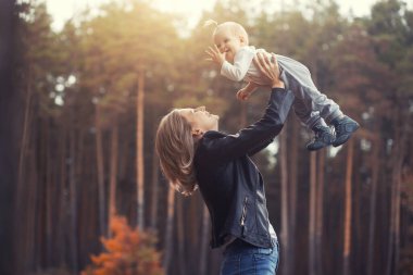 Sonbahar ormanında komik aile oyunları, anne çocuğu fırlatır.