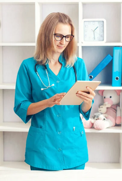 Young woman doctor with laptop in a turquoise coat in a clinical office. Health care concept.