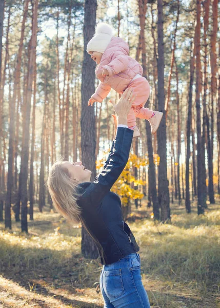 funny family games in the autumn forest, mother throws the child up