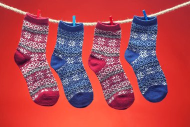 Sıcak örülmüş çoraplar kırmızı arka planda bir ipte. Noel Konseri