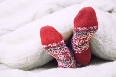 Noel kırmızı çorapları beyaz yatakta battaniyeyle kaplı. Kış tatilinin mutlu anları. Arkaplan, boşluğu kopyala.