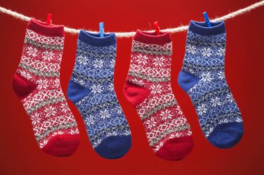Sıcak örülmüş çoraplar kırmızı arka planda bir ipte. Noel Konseri