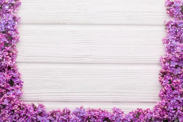 stock image Floral pattern of lilac branches on the white wooden table, flowers background. Flat lay, top view.