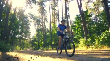 Mutlu sakallı adam dağ bisikletiyle güneşli ormanda bisiklet sürüyor. Macera seyahati.