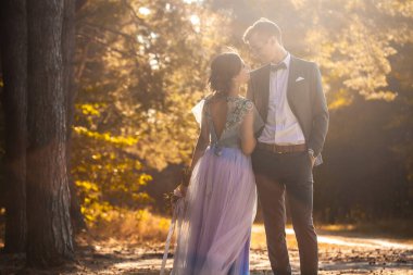 Mutlu gelin ve damat yeşil parkta yürüyor.