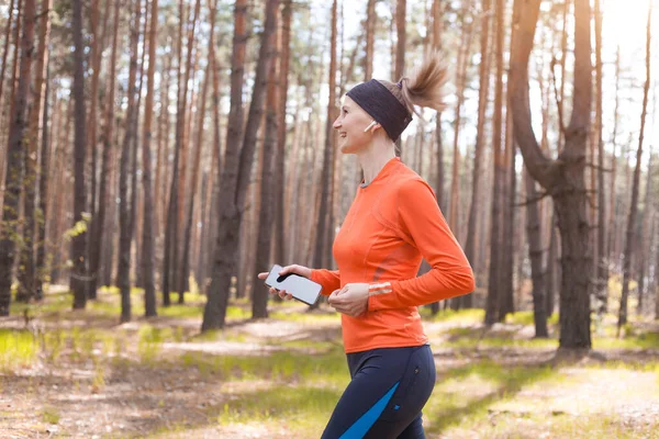 日当たりの良い松林の中を走る朝の少女 心臓のトレーニングと健康的なライフスタイル — ストック写真
