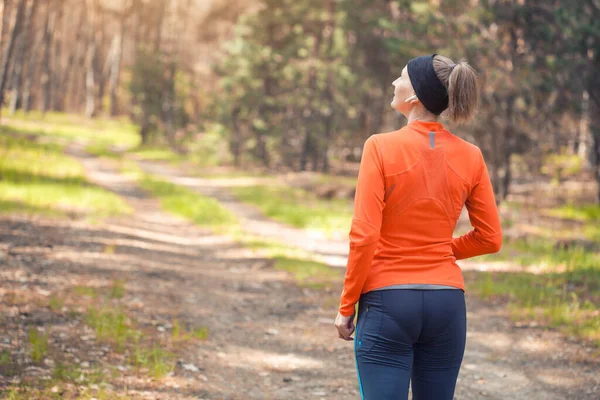 日当たりの良い松林の中を走る朝の少女 バックビュー 心臓のトレーニングと健康的なライフスタイル — ストック写真