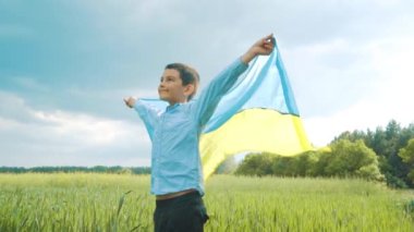 Ukrayna için dua et. Buğday tarlasını yöneten Ukrayna bayrağı taşıyan çocuk. Ulusal bayrak sallayan küçük çocuk barış için dua ediyor. Bağımsızlık Günü 'nü kutlayan mutlu çocuk.