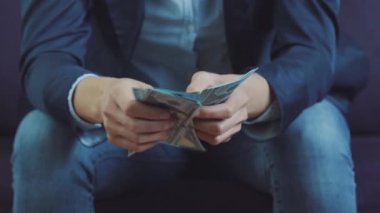 Resmi olarak kanepede oturan ve Amerikan Doları faturalarını sayan bir adam..