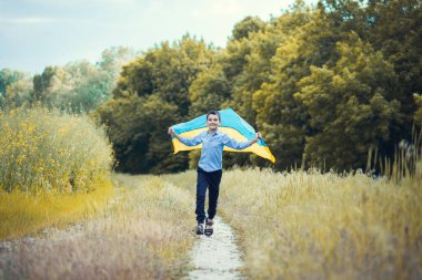 Ukrayna için dua et. Yaz parkını yöneten Ukrayna bayrağı taşıyan bir çocuk. Ulusal bayrak sallayan küçük çocuk barış için dua ediyor. Bağımsızlık Günü 'nü kutlayan mutlu çocuk.