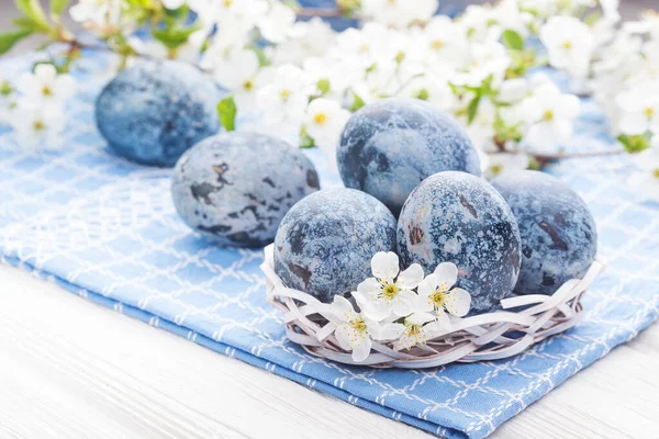 白い木のテーブルの上に桜の花と白いバケツにイースターブルーの大理石の卵 — ストック写真
